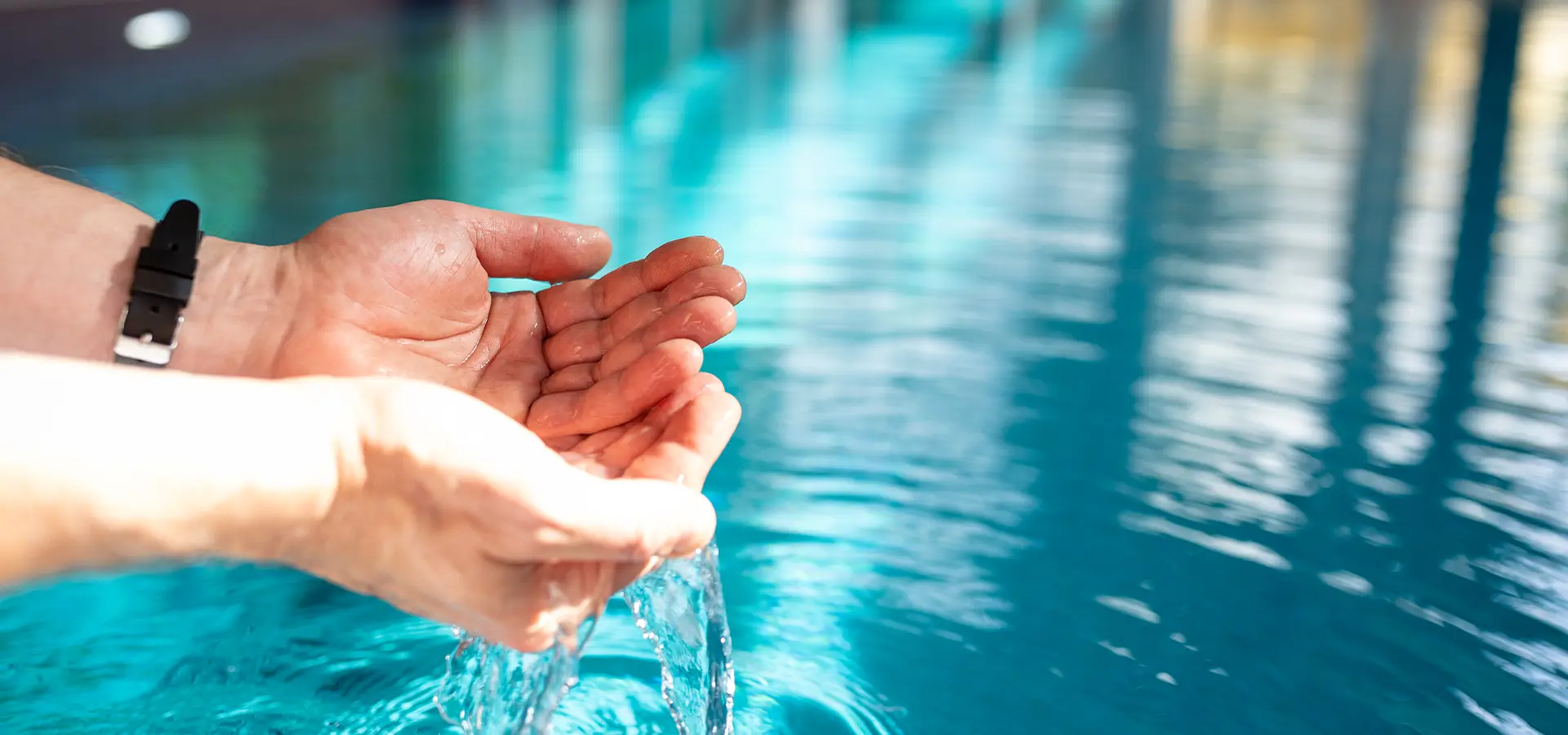 Hände die Wasser aus einem Becken schöpfen