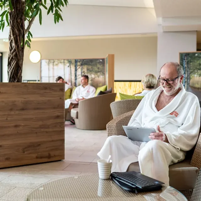 Ein Mann sitzt mit Tablet in einem Entspannungsraum